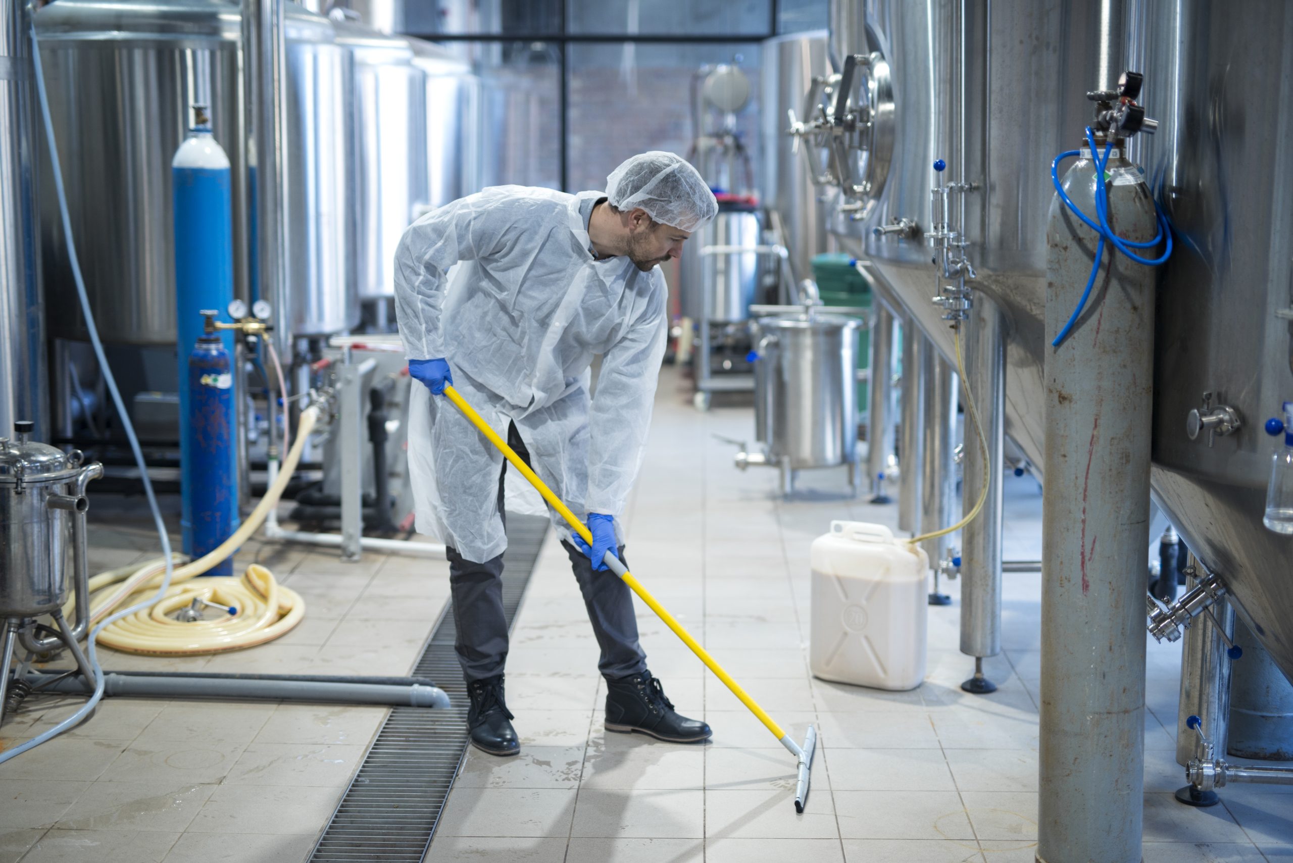 Limpiador industrial con uniforme de protección fregando el suelo de una planta alimentaria